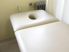 Empty white massage table in spa treatment room with soft lighting photo