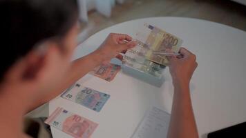Counting euro bills a person hands carefully count and arrange several euro banknotes on a table, showcasing different denominations in a detailed close-up shot. video