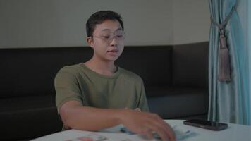 Man contemplating a pensive young man contemplates his thoughts, lost in reflection while holding a cup of coffee in his hands, a phone and a wallet on the table next to him, shot in a soft. video