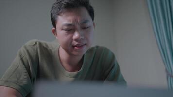 Focused man working on laptop. A young man intently focused on his laptop, illuminated by the soft glow of the screen. The image conveys concentration and dedication. video
