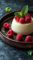 Creamy dessert topped with fresh raspberries and mint leaves on a textured plate photo