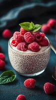 Delicious raspberry chia pudding topped with fresh berries and mint on a dark background photo