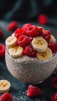 Delicious chia pudding topped with fresh raspberries and sliced bananas on a dark background photo