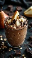 Chocolate pear smoothie topped with fresh pear slices and chocolate pieces on a dark background photo