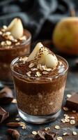 Delicious chocolate mousse topped with fresh pear slices and oats on a dark background photo