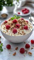 Delicious bowl of yogurt topped with fresh raspberries and granola on a light countertop photo