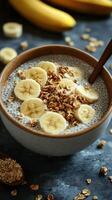 Healthy breakfast bowl with chia seeds, banana slices, and granola on a blue surface photo