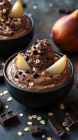 Chocolate mousse topped with pear slices and chocolate pieces served in elegant black bowls photo