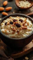 Creamy oatmeal topped with almonds and raisins served in a rustic wooden bowl photo