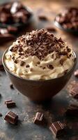 Creamy dessert topped with chocolate shavings in a dark bowl on rustic table photo