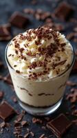 Delicious dessert layered with creamy vanilla and chocolate shavings prepared in a glass cup photo