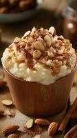 Creamy rice pudding topped with almonds and cinnamon served in a wooden bowl on rustic table photo