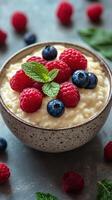 Creamy rice pudding topped with fresh raspberries, blueberries, and mint leaves on a textured surface photo
