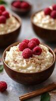 Creamy rice pudding topped with fresh raspberries and cinnamon served in wooden bowls on a gray surface photo