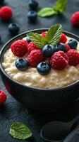 Delicious oatmeal topped with fresh berries and mint leaves on a dark background photo