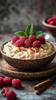 Creamy rice pudding topped with fresh raspberries and mint leaves in a rustic setting photo