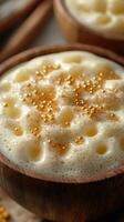 Rich and creamy beverage topped with golden bubbles in a wooden bowl during a cozy indoor setting photo