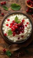 Creamy rice pudding topped with red currants and berry sauce on a rustic wooden table photo