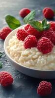 Delicious rice pudding topped with fresh raspberries and mint leaves on a textured surface photo