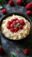 Delicious bowl of creamy rice pudding topped with fresh raspberries and mint leaves against a dark background photo