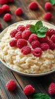 Creamy dessert topped with fresh raspberries and mint leaves arranged on a wooden table photo
