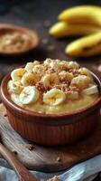 Creamy banana pudding topped with crushed cookies and fresh banana slices in a rustic wooden bowl photo
