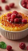 Delicious dessert with raspberries and caramelized top served in a white bowl on a pink surface photo