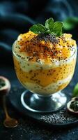 Delicious dessert with layered mango, chia seeds, and cream served in a glass bowl on a dark surface photo
