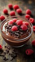 Chocolate mousse topped with fresh raspberries on a wooden table in warm lighting photo