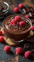 Delicious chocolate mousse topped with fresh raspberries and dark chocolate shavings on a wooden surface photo