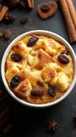 Warm bread pudding with raisins and spices served in a white bowl on a dark background photo