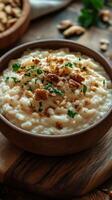 Creamy rice pudding topped with nuts and spices served in a rustic bowl on a wooden table photo