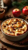 Warm bread pudding with apples and raisins served on a wooden table with festive decorations during autumn photo