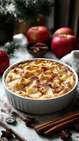Warm apple dessert topped with cinnamon and served in a white bowl, surrounded by fresh apples and spices photo