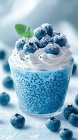 Blueberry dessert with whipped cream and fresh blueberries on top served in a clear glass cup photo