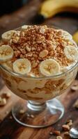 Delicious banana pudding with granola and banana slices served in a clear glass bowl photo