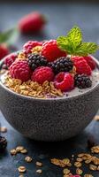 A bowl of yogurt topped with fresh berries and granola on a dark surface in a cozy kitchen setting photo