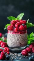 Creamy chia seed pudding topped with fresh raspberries and mint leaves placed on a dark background photo