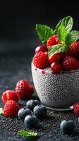 Chia seed pudding topped with fresh raspberries and blueberries in a decorative bowl on a dark textured surface photo