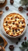 Delicious bread pudding with raisins and spices on a marble countertop surrounded by pine cones and natural elements photo