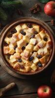 Baked dessert with bread cubes and raisins served in a wooden bowl on a rustic table photo