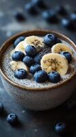 Fresh fruit bowl with blueberries, bananas, and chia seeds on a textured surface in a cozy setting photo
