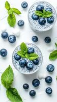 Blueberry chia pudding served in clear bowls with fresh mint on a white background photo
