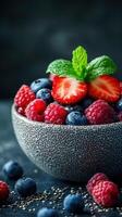 Fresh summer berries served in a textured bowl with a mint garnish on a dark background photo
