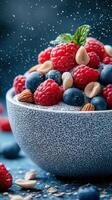 Fresh berry and nut bowl with chia seeds garnished with mint on a blue surface during daylight photo