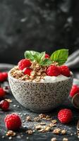 Bowl of yogurt topped with fresh raspberries and granola served on a dark surface photo
