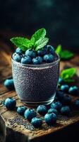 Healthy blueberry chia pudding served in a glass with fresh mint leaves on a wooden surface photo
