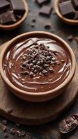 Rich chocolate ganache with chocolate chips displayed in a rustic bowl on a wooden surface photo