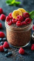 Chocolate chia pudding topped with fresh raspberries, blueberries, and banana slices on a dark surface photo
