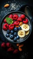 Chia seed pudding topped with fresh berries and banana slices served in a dark bowl photo
